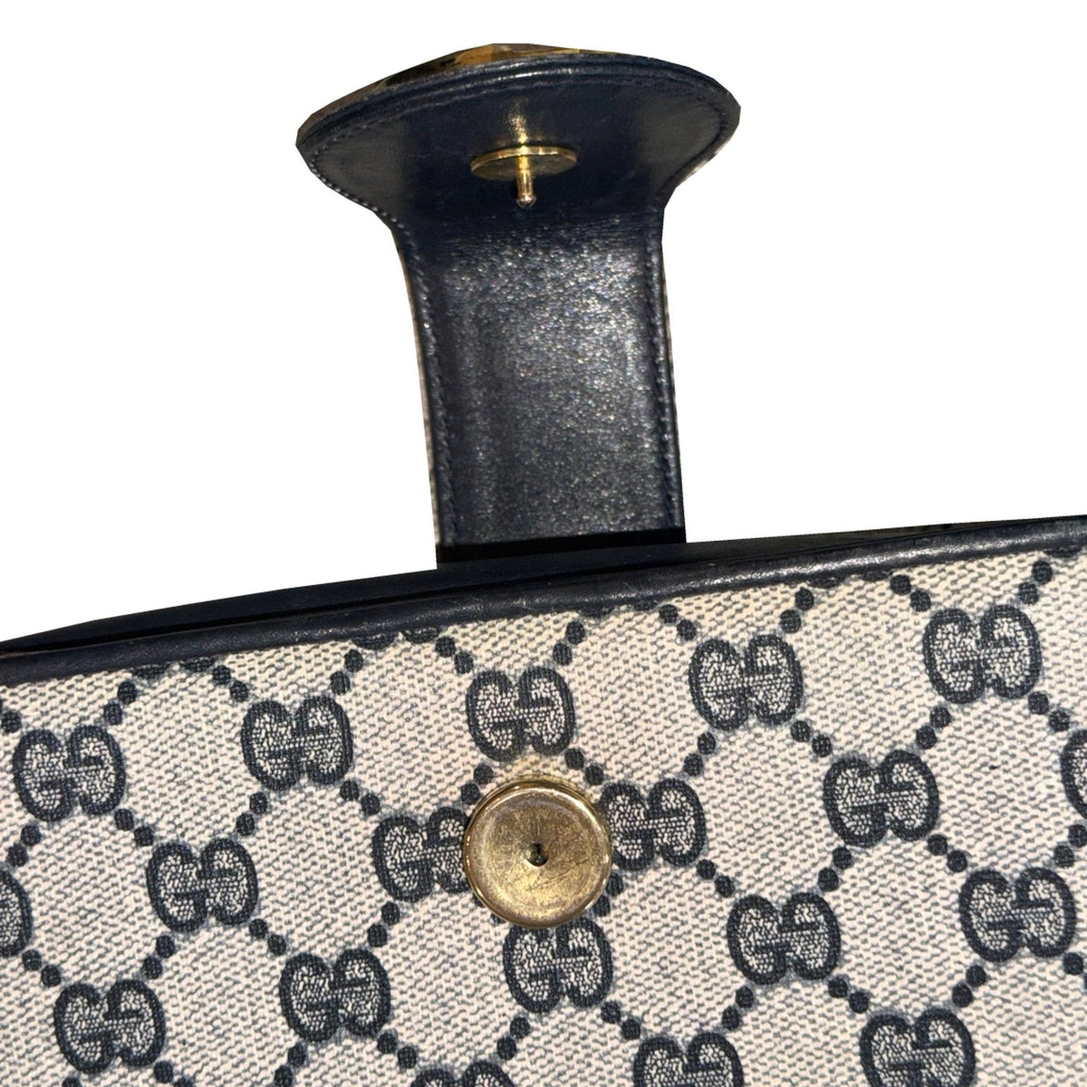 Close-up of the open Gucci clasp tab and gold-tone closure hardware on the GG monogram panel.