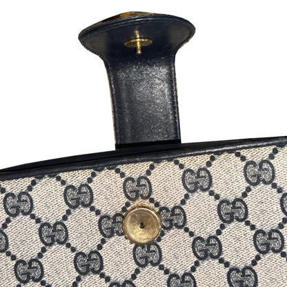 Close-up of the open Gucci clasp tab and gold-tone closure hardware on the GG monogram panel.