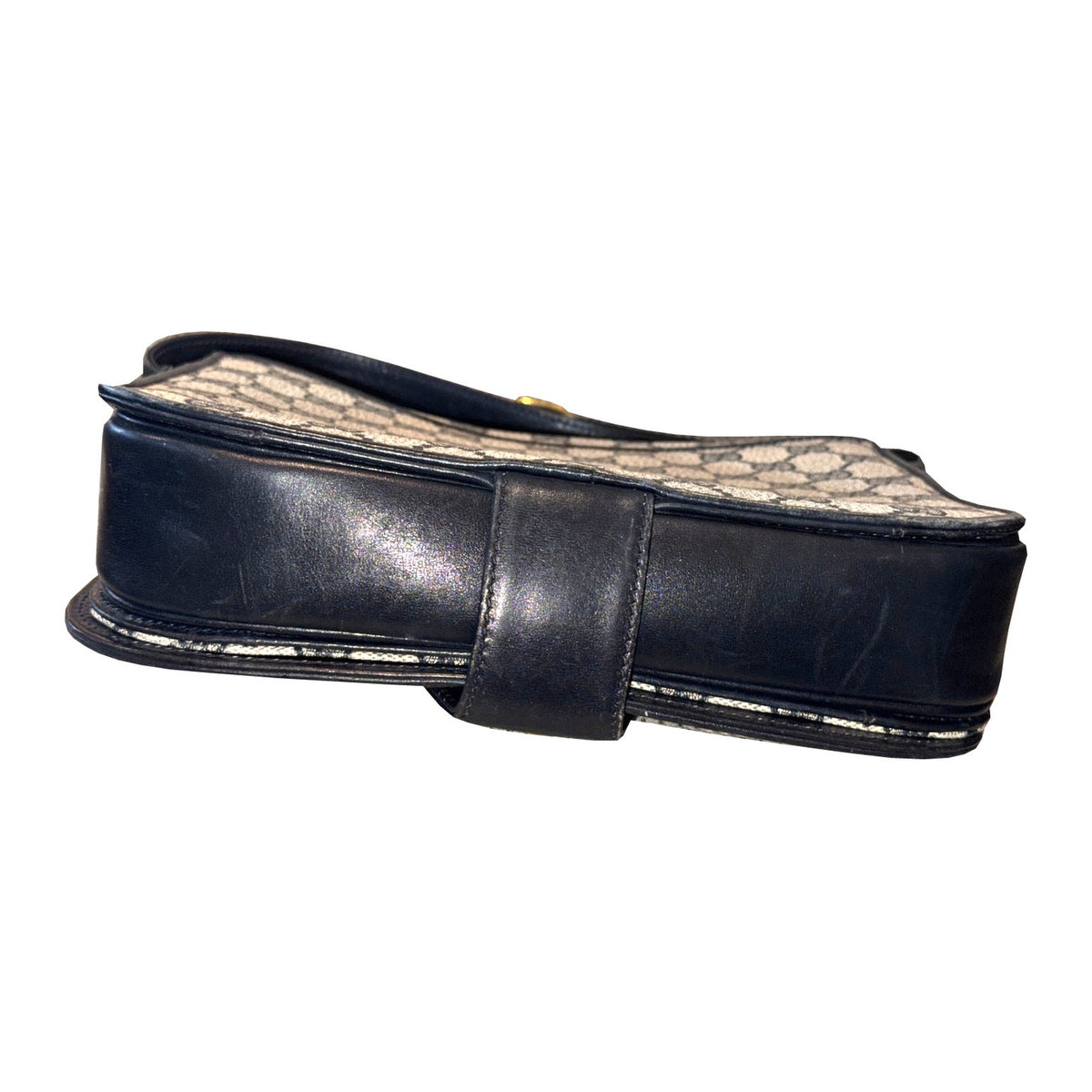 Bottom of the Gucci shoulder bag, showing navy leather, the clasp tab and wear along the piped edges.