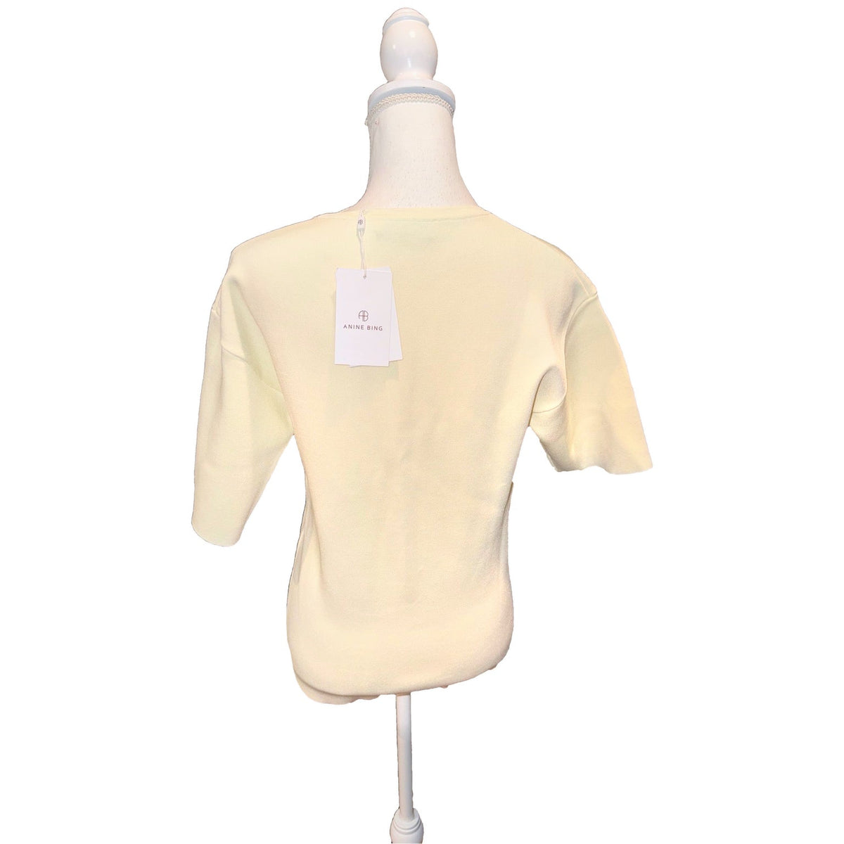 Back of the ivory ANINE BING Damion short-sleeve sweater with hangtag attached.