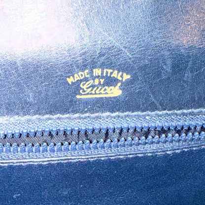 Gold Made in Italy by Gucci stamp above the interior zipper, with scratches visible on the blue lining.